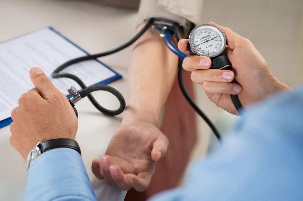 A doctor measuring a patient's blood pressure using a sphygmomanometer during a medical checkup.