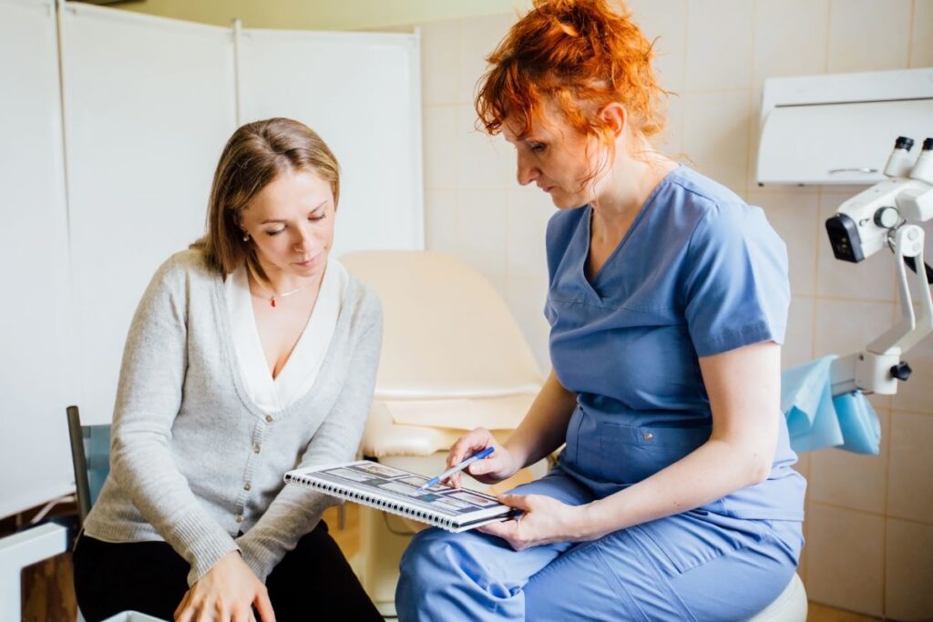 "Female doctor in blue scrubs discussing medical images with a patient in a clinic, representing patient consultation and care similar to the approach of Dr. Jai Bhagwan Dhull."