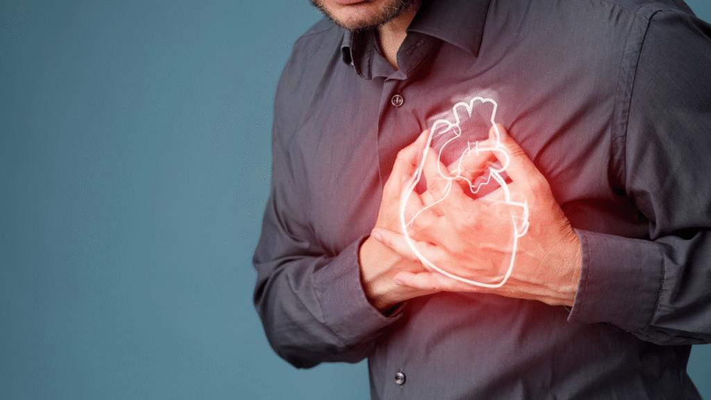 A man experiencing chest pain, holding his heart area with an illustrated glowing heart symbol, representing a possible heart attack — highlighting the importance of cardiac care and awareness as emphasized by Dr. Jai Bhagwan Dhull.