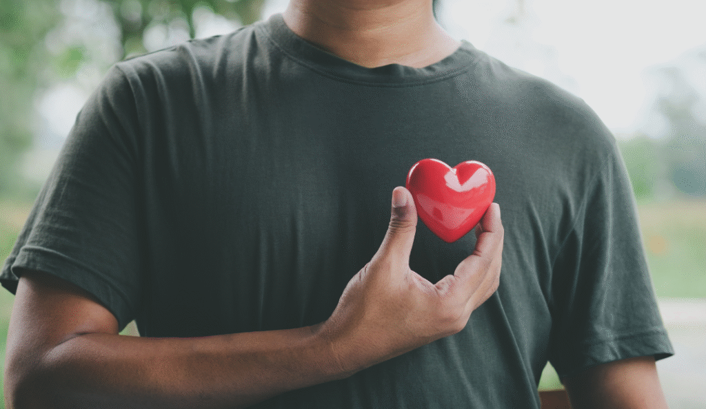 Person holding a red heart model close to the chest, symbolizing heart health and wellness — reflecting the importance of cardiac care emphasized by Dr. Jai Bhagwan Dhull.