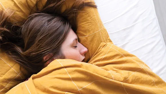 Woman sleeping peacefully under a warm blanket — Dr. Jai Bhagwan Dhull highlights the importance of quality sleep for maintaining heart health and overall wellness.