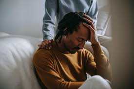 "Man sitting with his head in his hand showing signs of emotional distress, being comforted by another person, reflecting the compassionate mental health support approach of Dr. Jai Bhagwan Dhull."
