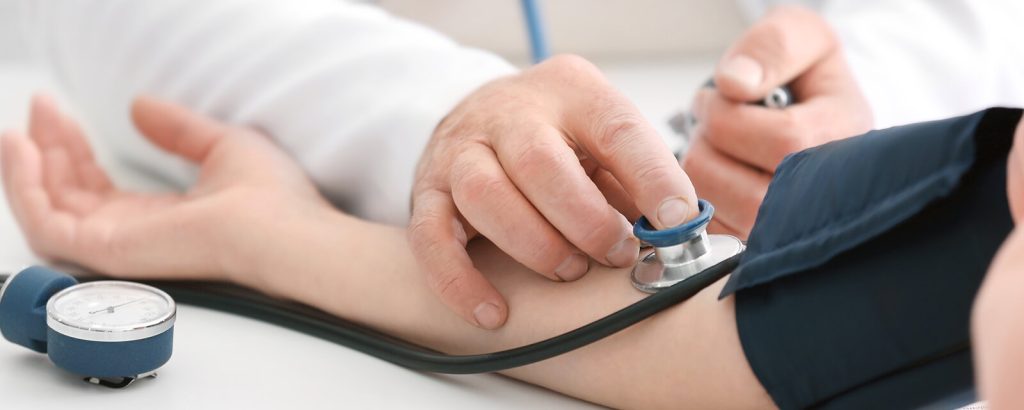 A doctor measuring a patient’s blood pressure using a sphygmomanometer and stethoscope — healthcare guidance by Dr. Jai Bhagwan Dhull.